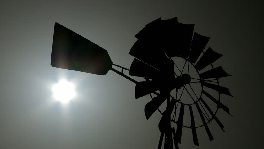 Vintage Windmill rotating in the wind with the sun shining in the background