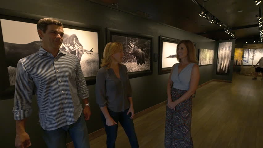 Three friends stroll through art gallery of landscape photography on Historic Main Street, Park City, Utah.