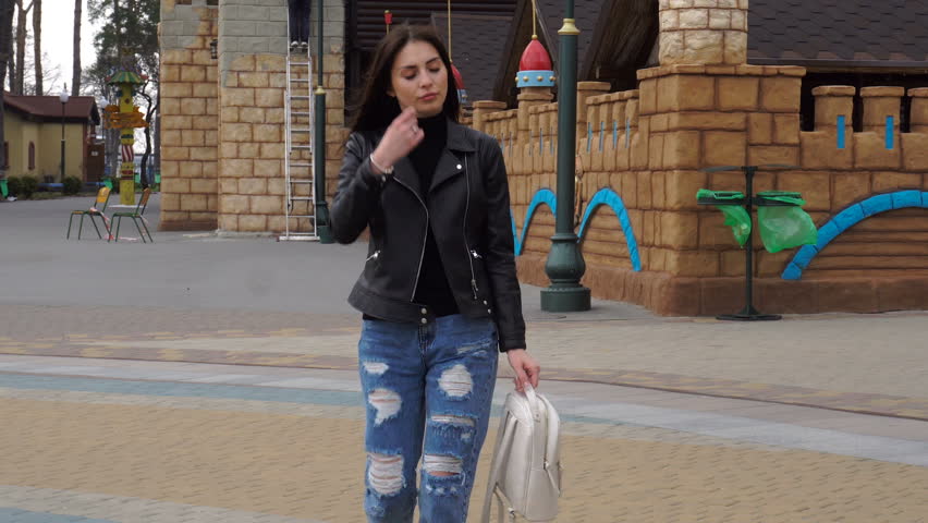 young charming brunette walks in the street and smiling into the camera