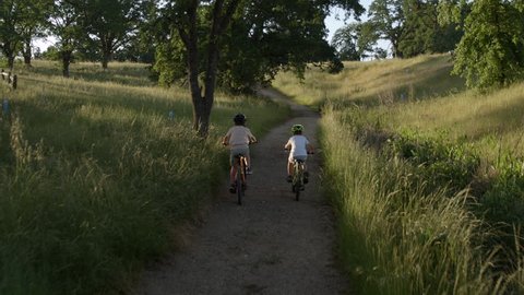 Two boys / brothers biking together on a nature trail, childhood and friendship