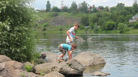 Two boys walk by the river in summer
