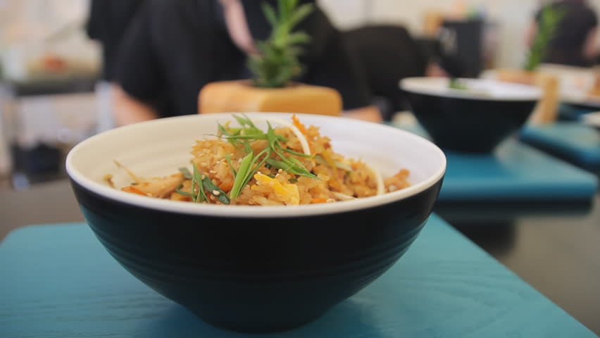 Cooked rice in a plate on a table, close up. Zooming camera. Traditional yellow rice with herbs and vegetables, healthy vegeterian food.