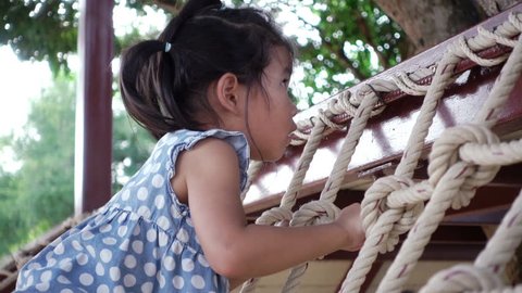 Adorable asian little girl be eager to know and slowly stand on climbing frame