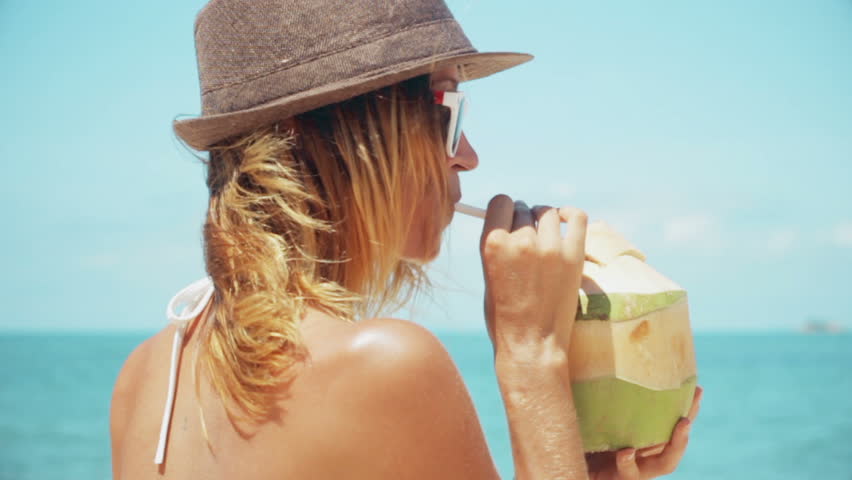 Woman drinking fresh coconut water with straw on beach fun vacation. Closeup of woman holding young green tropical fruit sipping for healthy snack during summer holidays in slow motion | Shutterstock HD Video #26151701