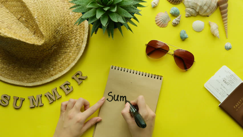 Young woman wriiting on here notebook. Trip mood. Top view. Yellow background.