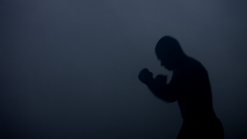 Boxer silhouette at dark studio. Silhouette of boxer training in dark. Mma fighter silhouette. Kickboxer training kick. Fighter mixed martial arts warming up before fight | Shutterstock HD Video #26153039