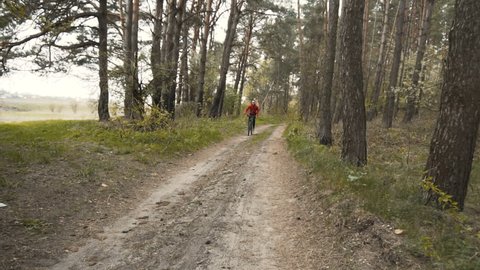 Young man rides the bike down forest sandy road, drift on the sand, 100FPS slowmotion