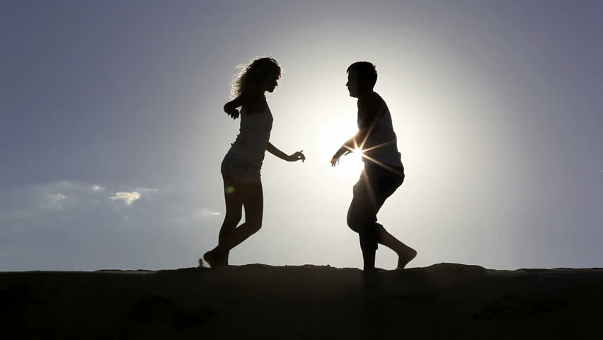 Romantic scene: happy couple dancing over sun with flying birds