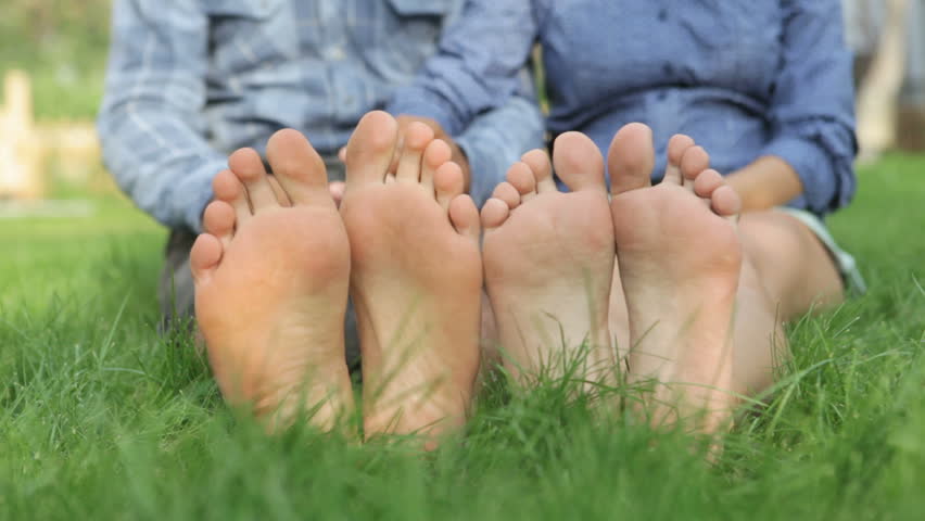 Loving couple resting on green grass with view on their feet