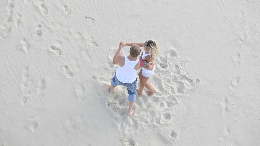 Joyful attractive couple dancing with love on the summer sand
