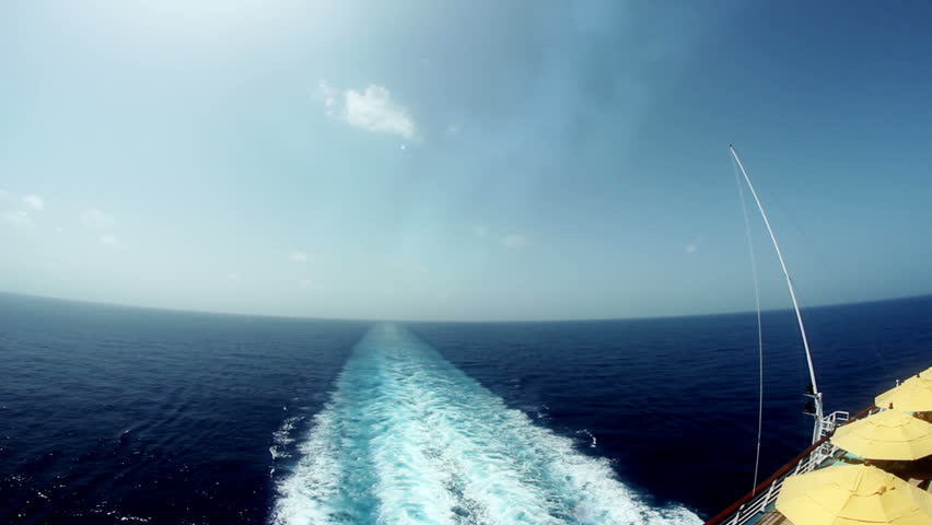 Looking out the back of a large cruise ship in the ocean.