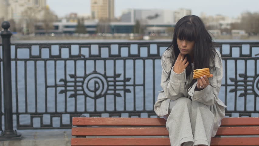 Young woman eating sandwich on bench