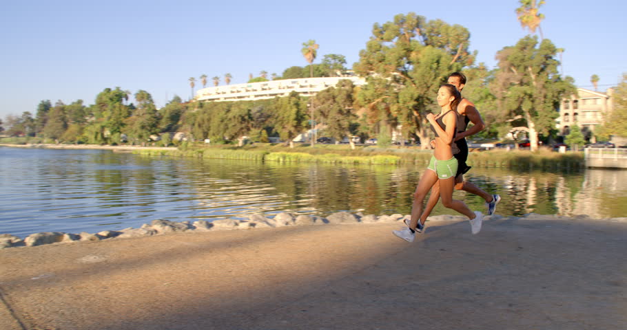 Athletic couple jogging in a park at dawn.