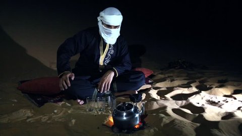 Tuareg man making tea in a desert at night