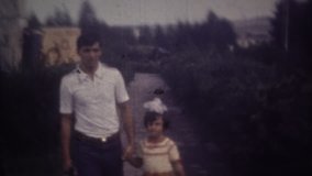 Family chronicle: Father walking with daughter and posing on 8mm retro camera. Father and daughter hugging and smiling.