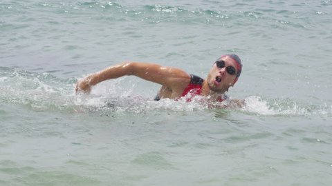 Triathlete man swimming freestyle crawl in ocean. Male triathlon swimmer swimming in professional triathlon suit training for ironman.