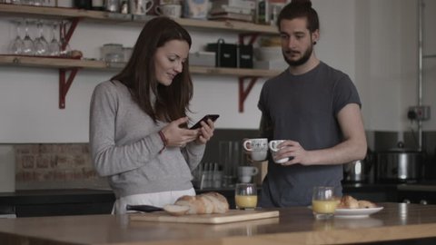 Young couple looking at smartphone together over breakfast