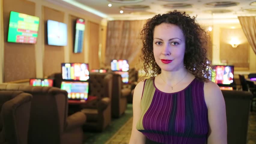 Woman with curly hair standing in game room of bookmaker club
