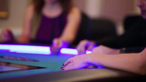 Hands of three people playing on the electronic poker table in the casino