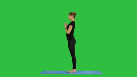 Young woman doing yogic sun salutation pose on mat on a Green Screen, Chroma Key