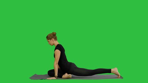 Young beautiful woman doing yoga pose, stretching her body on a Green Screen, Chroma Key