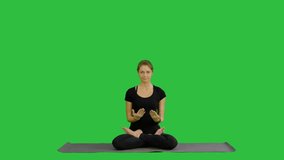 Woman practicing yoga in lotus pose with namaste hands gesture on a Green Screen, Chroma Key