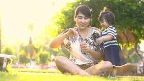 Asian Mother entertaining her baby girl by making iridescent soap bubbles