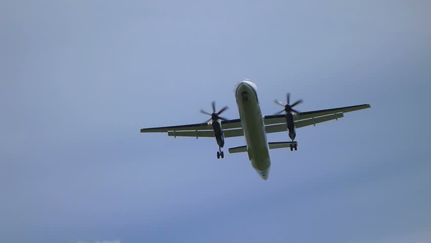 Commercial passenger airplane flying overhead on sunny day.