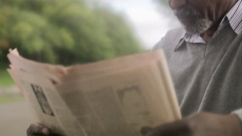 A man sitting on a bench reading a newspaper Stock Video