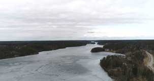 Nuuksion pitkajarvi, Cinema 4k landing aerial view of icy pitkajarvi lake, on a cloudy spring day, in nuuksio national park, in Espoo, Finland