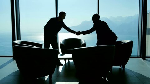 lobbyist handshaking with partner after business deal agreement. businessman meeting in modern lobby talking together. two people having a conversation about financial strategy 