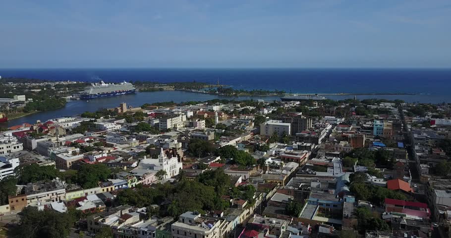 Forward aerial flight across Dominican Republic neighborhoods toward the harbor and a distant cruise ship on the Caribbean coast, 2017.