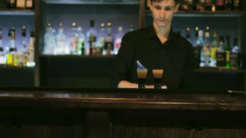 The barman prepares a cocktail and sets it on fire