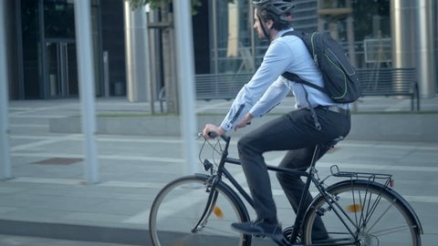 Confident male worker in shirt with a backpack commuting to a job. Smart handsome cyclist traveling by sustainable transport and living a healthy lifestyle.