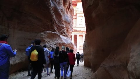 JORDAN, PETRA, DECEMBER 5, 2016: People near Al Khazneh or the Treasury at ancient Petra - historical and archaeological city in Hashemite Kingdom of Jordan. View from Siq - long narrow passage, gorge