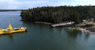 Skåldö cable ferry, Cinema 4k aerial view of a yellow cable ferry, closing in to dock, at the harbor, in Skaldo, in the tammisaari archipelago, in Finland