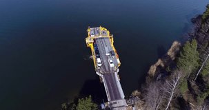 Skåldö cable ferry, Cinema 4k aerial orbit view of a cars leaving a yellow cable ferry, at the harbor, in Skaldo, in the tammisaari archipelago, in Finland