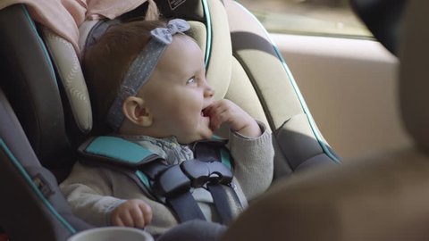 Adorable Smiley Baby Girl Sits In Her Car Seat, She Looks Out Window, And Around Car