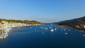 landscape Greek island of Poros amidst the Mediterranean, with a bird's-eye view, aerial video shooting, many moored to the pier, sailing yachts, catamarans, the strait between the islands, a