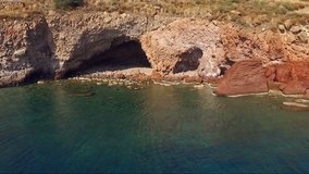 Landscape of grottoes in cliffs, mountains, cliffs. Water washed deep grottos. Greek islands in the Mediterranean, aerial video shooting, bird's eye view, summer sunny day