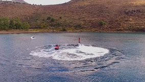 The man is having fun, flying over the water on a flyboard, under the pressure of water. Aerial video shooting, bird's eye view, wild bay of the Mediterranean Sea, near the Greek island.picture of