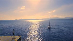 Sunset in an empty Greek marina, Methana, Mediterranean Sea. Aero video shooting, A lone sailing yacht comes into the marina. In the background, a landscape from the sea, a clear blue sky, a sunny