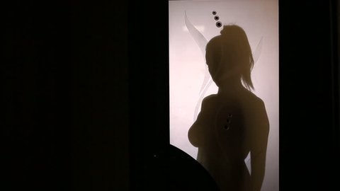 Silhouette of a woman changing clothes behind a glass door. She takes off her underwear