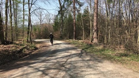 Middle aged woman on e-bike passing by on rough forest path - symbol for new mobility concepts