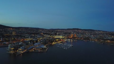 Aerial drone footage over Aker Brygge and City Hall in Oslo, Norway at night in 2018