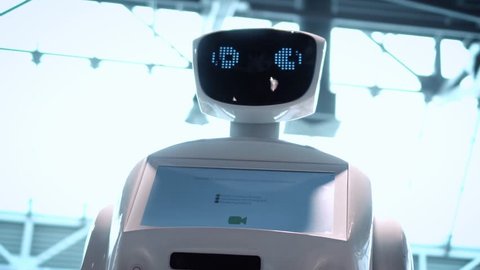 Modern Robotic Technologies. The robot looks at the camera at the person. The robot shows emotions. Raises his hands up, dances or is indignant. Or attacks