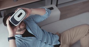 Caucasian male in casual clothes using his VR headset indoors, watching 360 video at home. 4K UHD RAW edited footage 