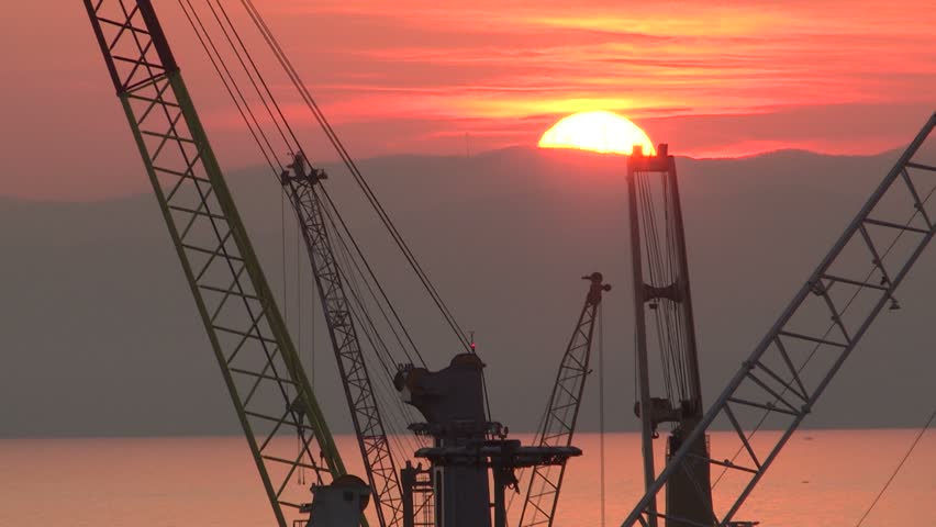 a cool orange sun sets over cranes
 / Sunset over cranes / GENOA, ITALY – MARCH 14  2017


