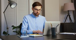 Young man typing on his laptop. Serious man working on laptop on office. Office background.