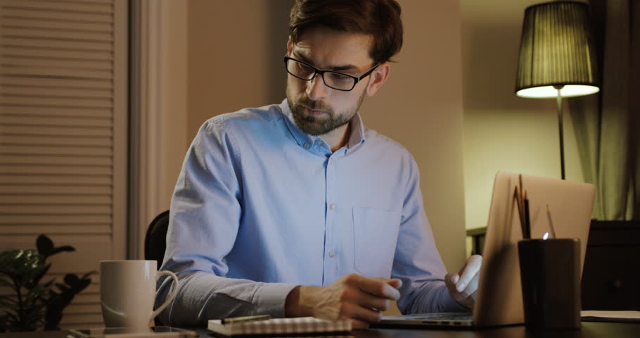 Young man typing on his laptop. Thinking business man working in office. Young business man thinking in office.